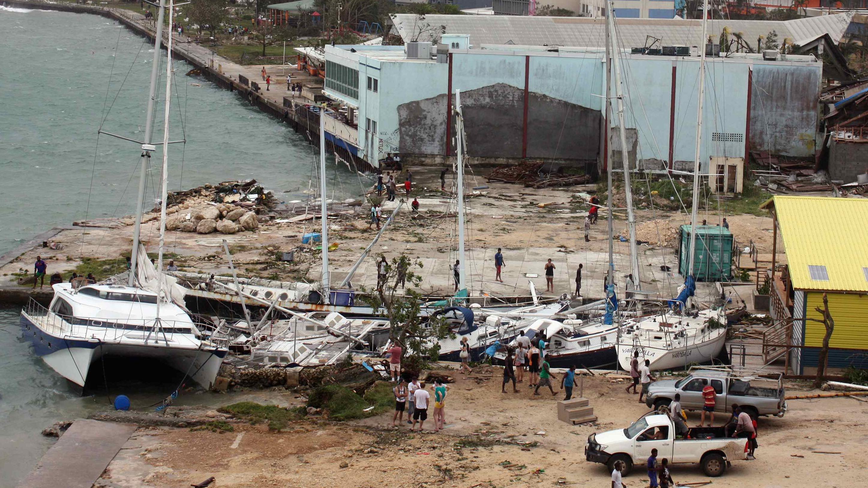 Local residents look at damaged boats washed up into a small inlet in Port Vila, the capital city of the Pacific island nation of Vanuatu, March 14, 2015.