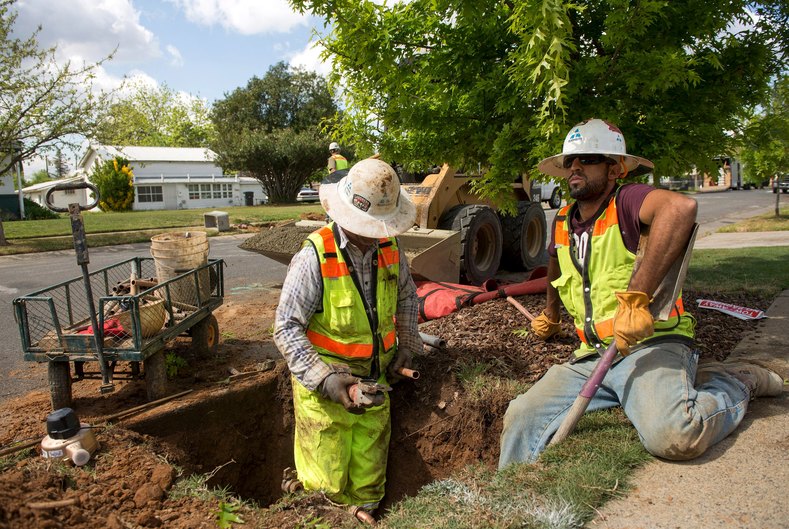 Teichert Construction laborer Israel Moreo (L) and plumber Victor De Anda install a water meter on 21st Street during the city's water meter retrofitting program in Sacramento, April 8, 2015.