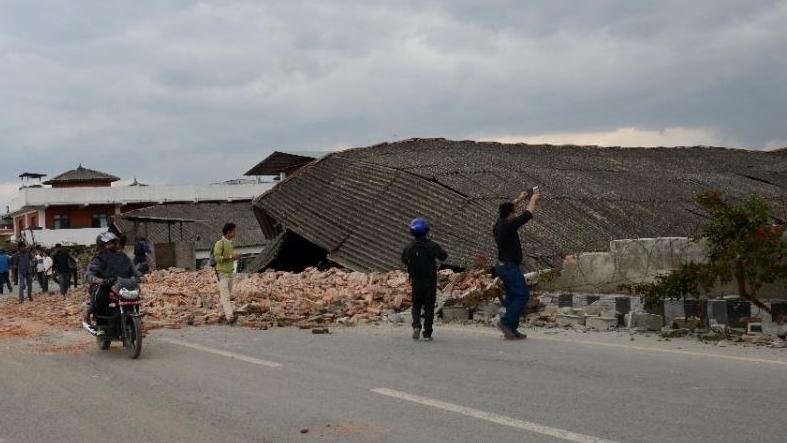 Nepalese people walk past a collapsed building in Kathmandu, on April 25, 2015. 