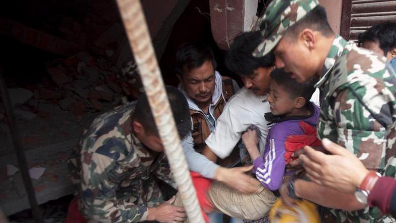 Volunteers carry an injured boy after rescuing him from the debris of a building that was damaged in an earthquake in Kathmandu, Nepal, April 25, 2015.