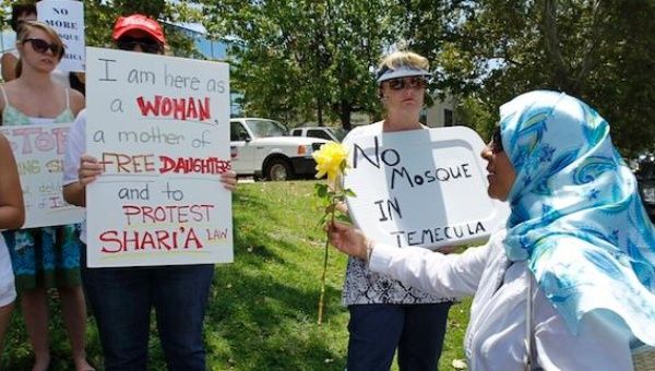 A Muslim woman offers a flower to protesters against mosques in the U.S.