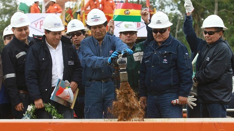 Bolivian President Evo Morales (C) turns on the tap at the new oil reserve.