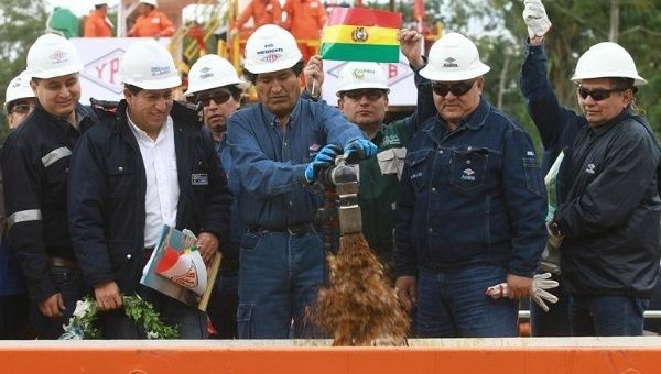 Bolivian President Evo Morales (C) turns on the tap at the new oil reserve.