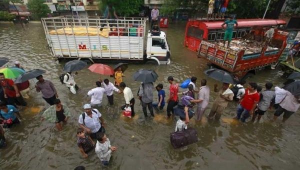 People walk through flooded roads as vehicles are seen stuck in a traffic jam due to heavy rains in Mumbai, on June 19.