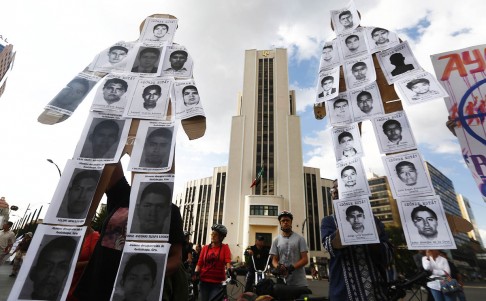 Mexico protesters hold two large effigies covered with photos of missing students that read