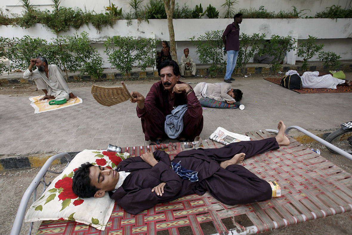 A man uses a handheld fan to cool down his son, while waiting outside Jinnah Postgraduate Medical Centre in Karachi.