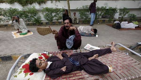 A man uses a handheld fan to cool down his son, while waiting outside Jinnah Postgraduate Medical Centre in Karachi.