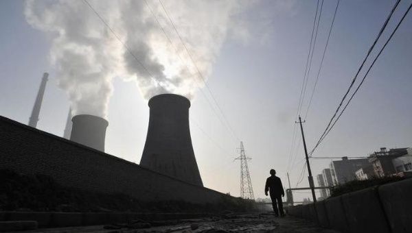 A man walks past a coal-burning power plant in Xiangfan, Hubei province Nov. 19, 2010