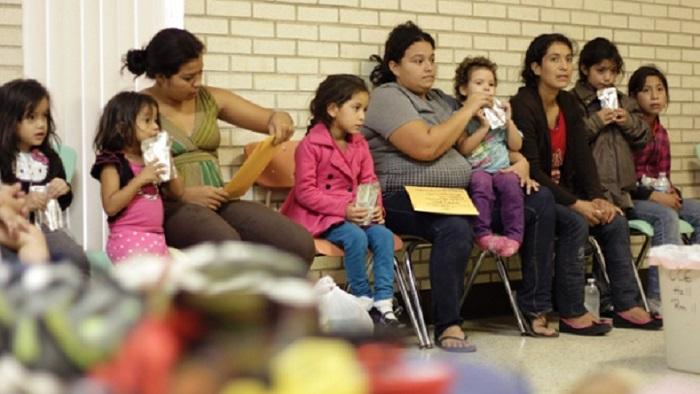 Migrants sit at the Sacred Heart Catholic Church temporary migrant shelter in McAllen, Texas June 27, 2014.