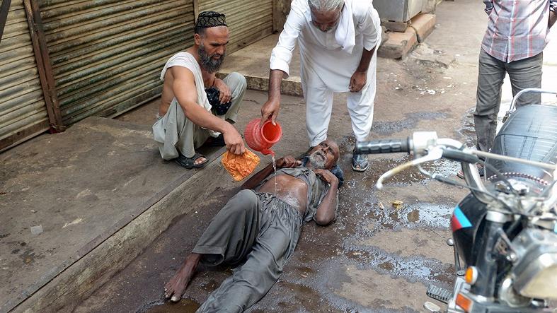 People help a man suffering from heat exhaustion at a market in Karachi.