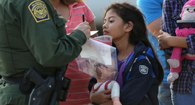 Salvadorian immigrant watches as a US Border Patrol agent records family information.