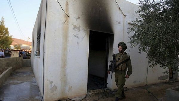 An Israeli soldier walks past a house that had been torched in a suspected attack by Jewish extremists, Nablus July 31, 2015.