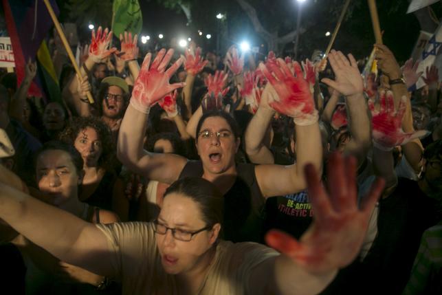 Protesters hold up gloves covered in red during a protest against the violence towards the gay community in Tel Aviv August 1, 2015.