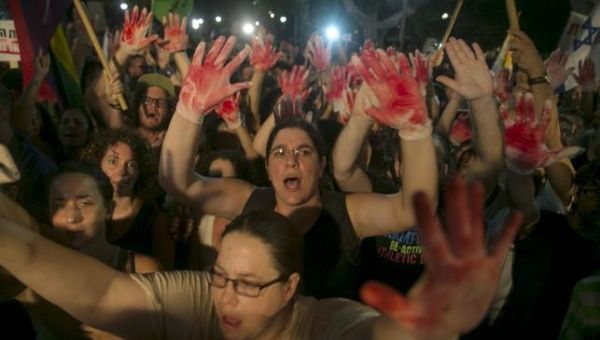 Protesters hold up gloves covered in red during a protest against the violence towards the gay community in Tel Aviv August 1, 2015.