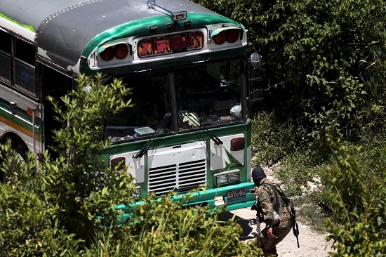 A soldier takes a picture of a bus that was attacked by suspected gang members in San Pedro Perulapan, El Salvador Aug. 5, 2015.