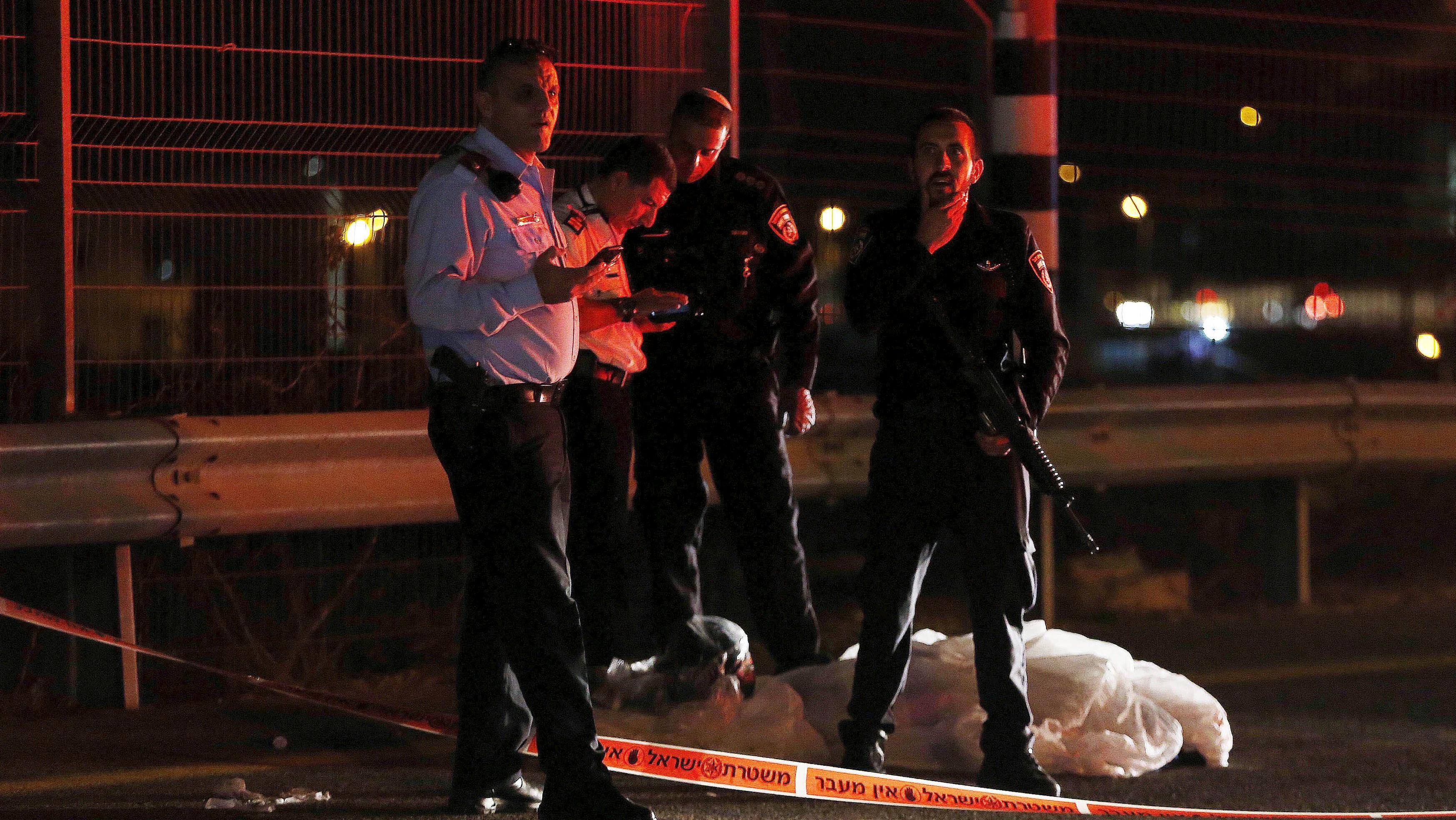 Israeli policemen stand near the body of a Palestinian following an alleged stabbing attack in the occupied West Bank along a main highway near Jerusalem August 9, 2015. Israeli troops shot dead the Palestinian who allegedly stabbed an Israeli man at a petrol station in the occupied West Bank on Sunday along a main highway near Jerusalem, police said.