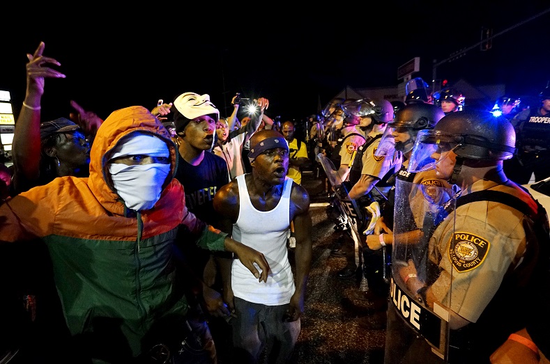 Protesters yell at a police line shortly before shots were fired in a police-officer involved shooting in Ferguson, Missouri August 9, 2015.