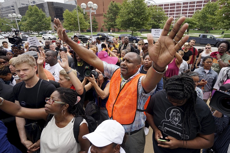 Protesters pray at the federal courthouse in downtown St. Louis August 10, 2015. Authorities declared a state of emergency in Ferguson, Missouri, after gunfire erupted on the anniversary of a high-profile police shooting and prosecutors on Monday charged an 18-year-old man with assault on officers.