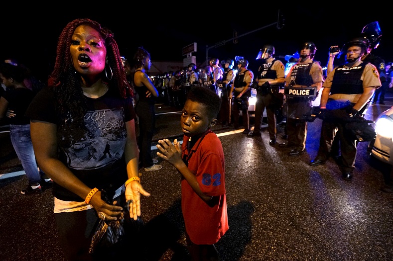 Amarion Allen, 11-years-old (C), and his mother Amima stand in front of a police line shortly before shots were fired in a police-officer involved shooting in Ferguson, Missouri August 9, 2015. 