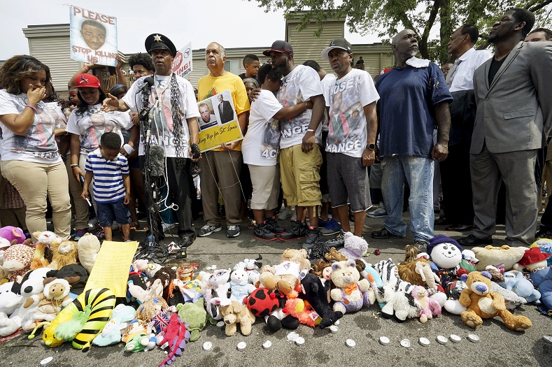 Michael Brown Sr. (C), at the spot where his son was killed, hugs his wife Cal Brown at an event to mark the one-year anniversary of the killing of his son Michael Brown in Ferguson, Missouri August 9, 2015. Hundreds of people marched, prayed and held moments of silence in Ferguson, Missouri on Sunday to mark the anniversary of the shooting death of an unarmed black teenager by a white police officer a year ago.