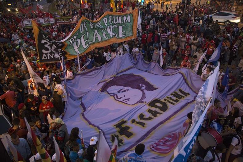 Participants carry a massive banner that reads 