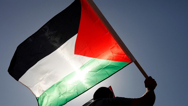 A man raises the flag of Palestine