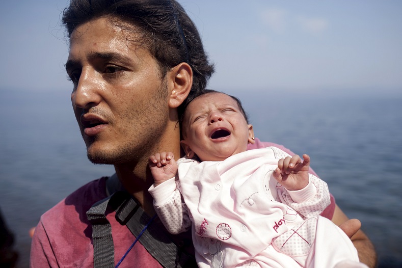 A Syrian refugee from Aleppo holds his one month old daughter moments after arriving on a dinghy on the Greek island of Lesbos, September 3, 2015.