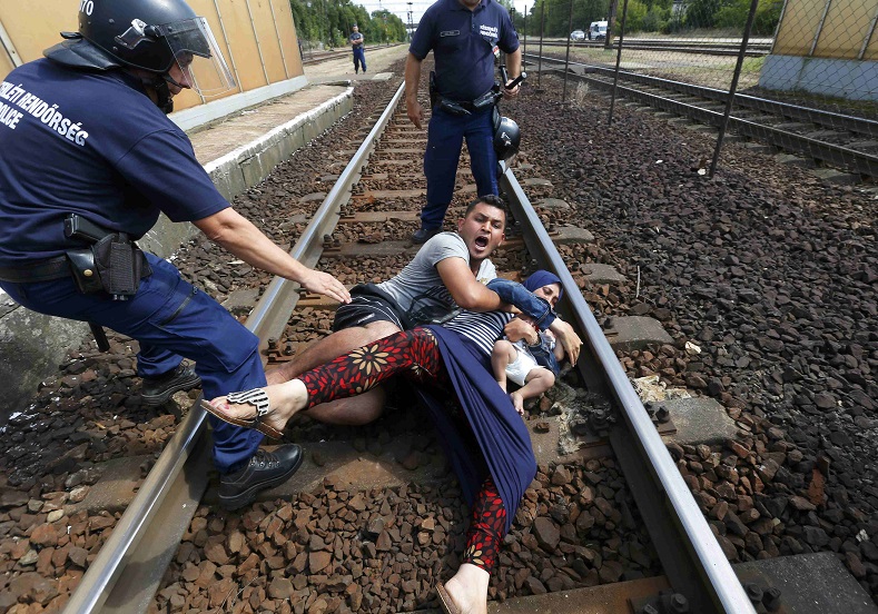Hungarian policemen stand by the family of refugees as they wanted to run away at the railway station in the town of Bicske, Hungary, September 3, 2015. 