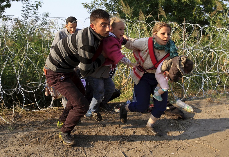 Syrian refugees run after crossing under a fence as they enter Hungary, at the border with Serbia, near Roszke, August 27, 2015. Hungary made plans on Wednesday to reinforce its southern border with helicopters, mounted police and dogs, and was also considering using the army as record numbers of migrants, many of them Syrian refugees, passed through coils of razor-wire into Europe.