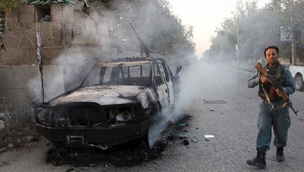 An Afghan policeman patrols next to a burning vehicle in the city of Kunduz after U.S. tragic bombing of hospital.