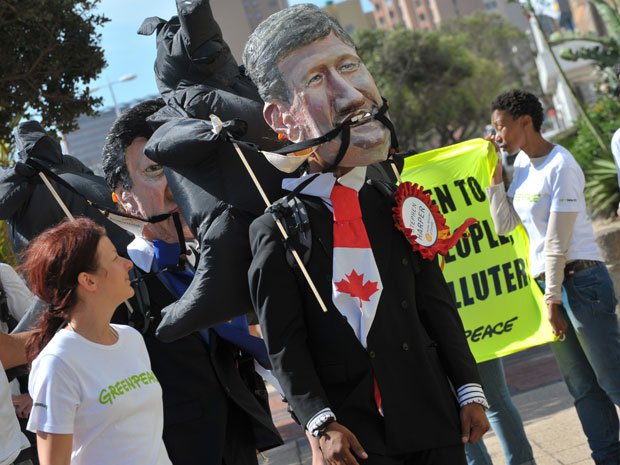 An activist wearing a Stephen Harper mask marches at a protest outside of a UN climate conference.