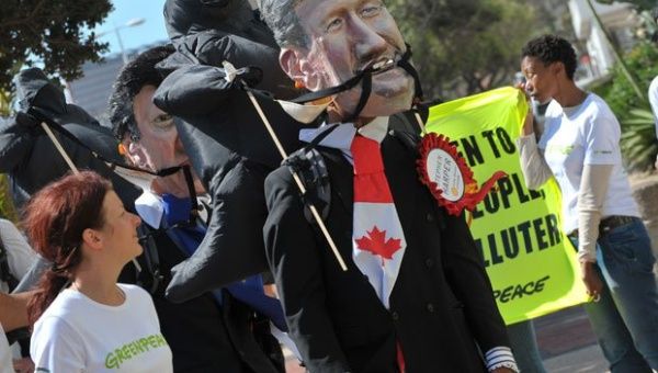 An activist wearing a Stephen Harper mask marches at a protest outside of a UN climate conference.