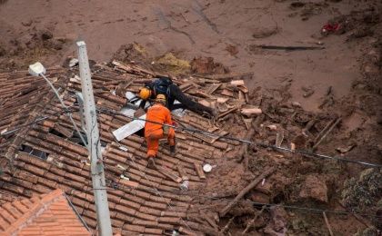 Firefighters on a shattered rooftop search for survivors after a dam at a mining waste site burst, smothering the village of Bento Rodrigues, Brazil, on Nov. 6, 2015 