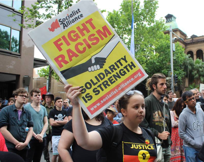 A protester holds a sign urging people to combat racism.