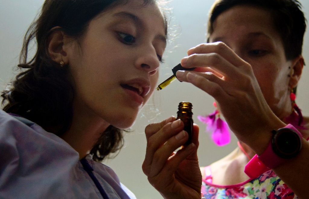 Ines Cano administers medical marijuana to her daughter Luna Valentina (L) at their home in Medellin on November 25, 2015; Valentina, 12, was born with refractory epilepsy and uses cannabis to calm her seizures.