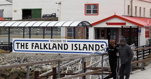 Argentine Falklands War veterans Hugo Romero (R) and Walter Sarverry walk next to a ''Welcome to the Falkland Islands'' sign in Port Stanley, March 14, 2012.