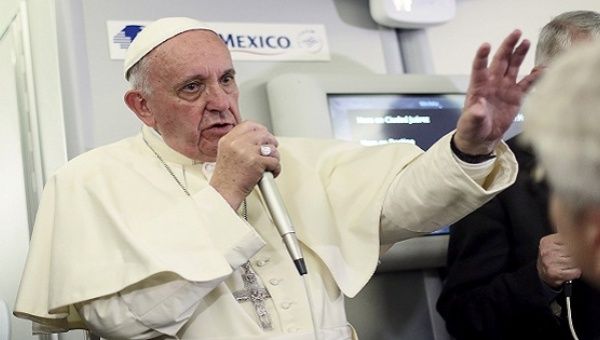 Pope Francis gestures during a meeting with the media on board the papal plane while en route to Rome.