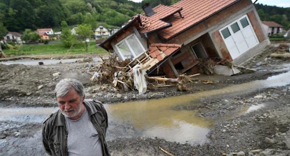 A man stands near house damaged by flooding and landslides in Krupanj on May 20, 2014,