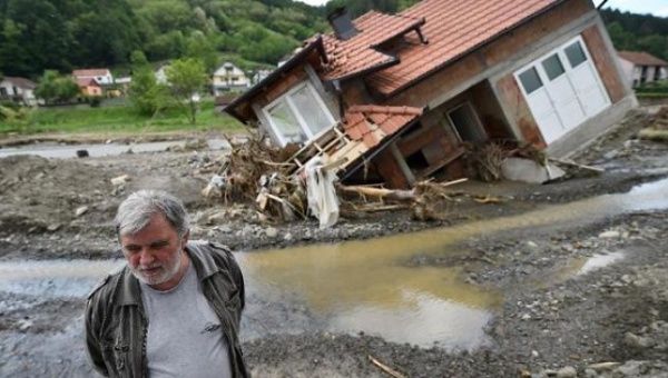 A man stands near house damaged by flooding and landslides in Krupanj on May 20, 2014,