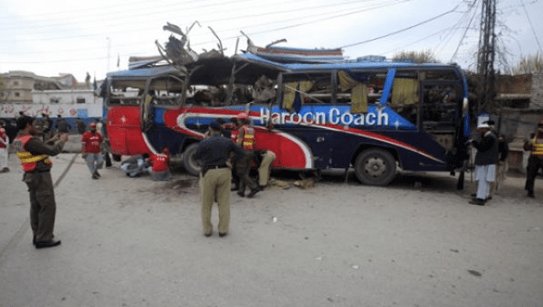 Policemen and rescue officials walk near a bus damaged in a bomb blast in Peshawar, Pakistan March 16, 2016