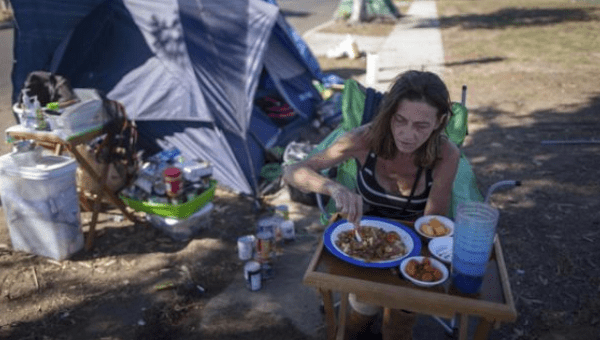 Stacie McDonough, 51, eats lunch by her tent in a homeless RV and tent encampment near LAX airport in Los Angeles, California, United States, Oct. 26, 2015.