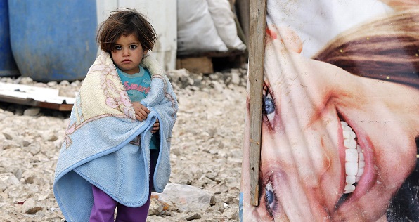 A young Syrian refugee covers herself with a blanket as she stands outside tents at a makeshift settlement in Bar Elias in the Bekaa valley