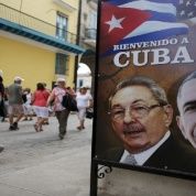 Tourists pass by images of U.S. President Barack Obama and Cuban President Raul Castro in a banner that reads 