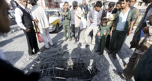 People look at a hole caused by a Saudi-led air strike on a bridge in Yemen's capital Sanaa.