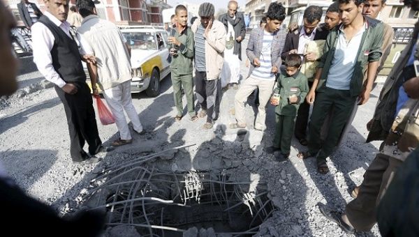 People look at a hole caused by a Saudi-led air strike on a bridge in Yemen's capital Sanaa.