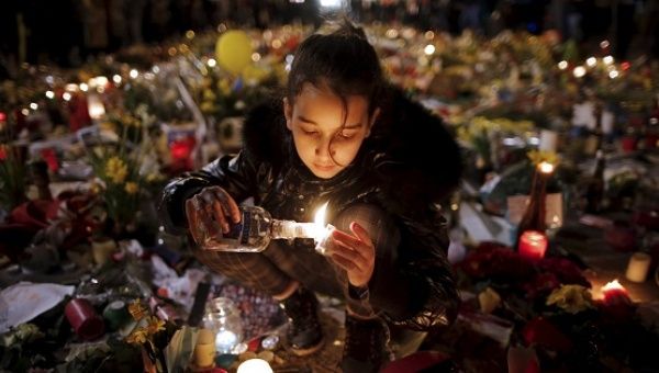 A girl lights candles as people pay tribute to the victims of Tuesday's bomb attacks, at the Place de la Bourse in Brussels, Belgium, March 26, 2016.