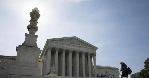 A woman walks to the Supreme Court in Washington June 19, 2014.