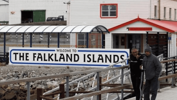 Argentine Malvinas War veterans Hugo Romero (R) and Walter Sarverry walk next to a ''Welcome to the Falkland Islands'' sign in Port Stanley, March 14, 2012.