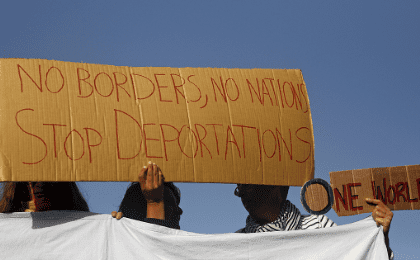 Activists hold placards as they protest against the return of migrants to Turkey, at the port of Mytilene on the Greek island of Lesbos, April 4, 2016.