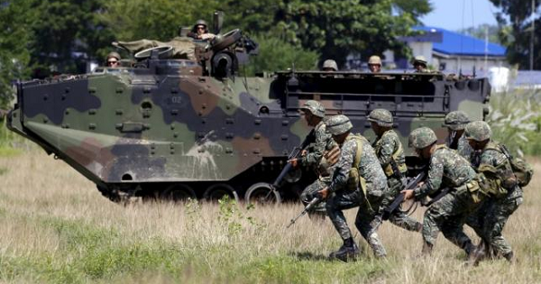 U.S. soldiers aboard an amphibious armoured vehicle watch as Philippine marine troops run during assault exercises in joint drills aimed at enhancing cooperation between the allies at a Philippine Naval base San Antonio, Zambales Oct. 9, 2015.